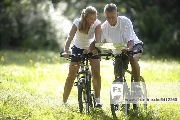 Couple reading a map during bicycle trip  woman  42 years  man  52 years