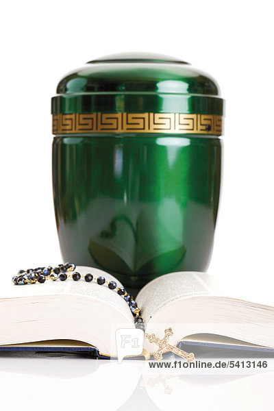 Opened Bible and rosary set in front of a green urn