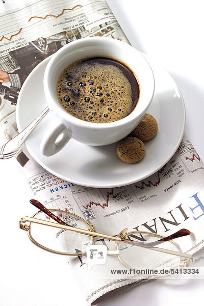 Cup of espresso and glasses on top of a business journal