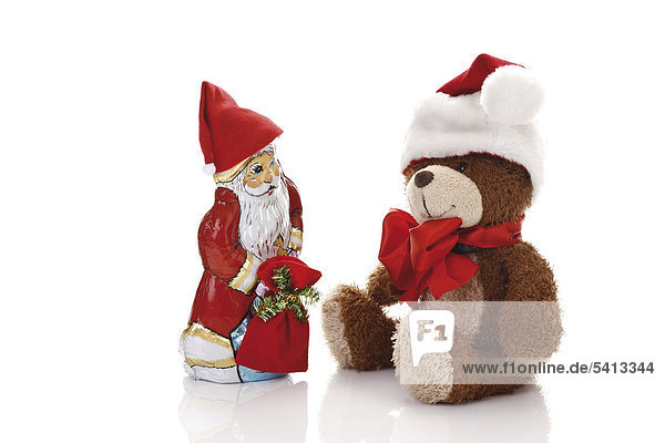 Teddy bear wearing a Christmas cap and a chocolate Santa Claus