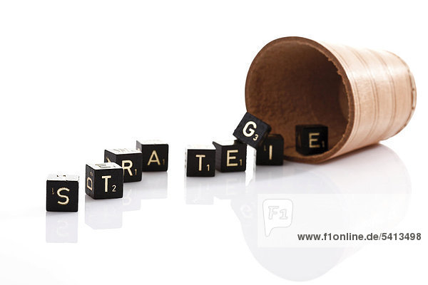 Dice shaker and lettered dice which spell Strategie  German for Strategy