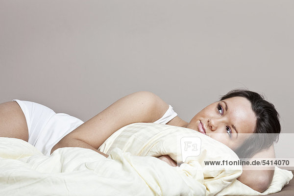 Junge Frau liegt auf einer Bettdecke