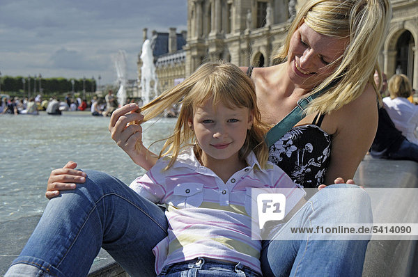Young mother with her daughter on a city trip sitting in front of the Louvre in Paris  France  Europe