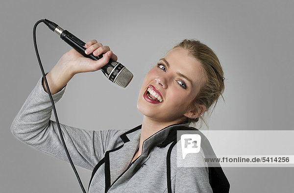 Young woman holding a microphone in a singer pose mouth