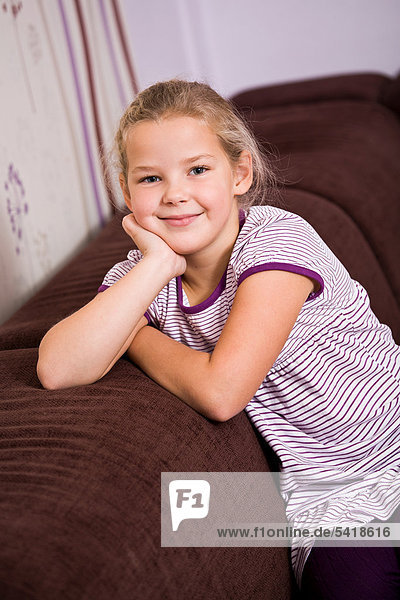 8-jähriges Mädchen sitzt auf Sofa