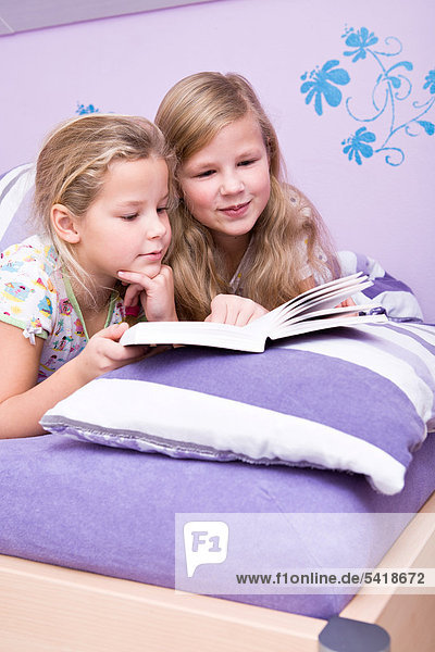 Zwei Mädchen  Schwestern lesen im Bett