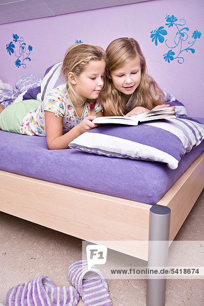 Zwei Mädchen  Schwestern lesen im Bett
