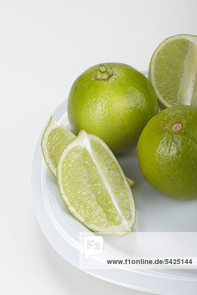 Limetten (Citrus latifolia) auf einem weißen Teller