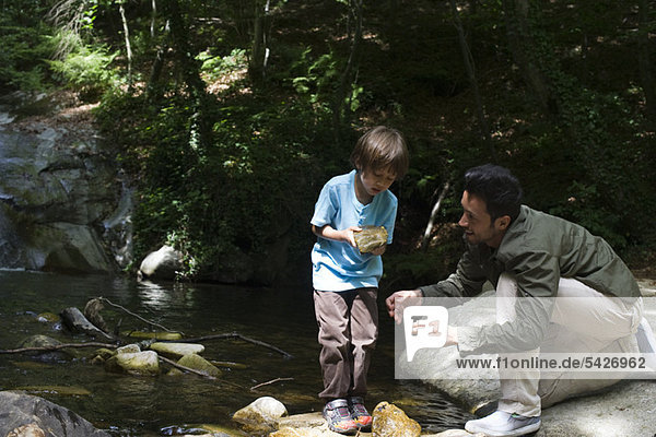 Vater und Sohn erkunden die Natur  Junge hält den Stein in der Hand