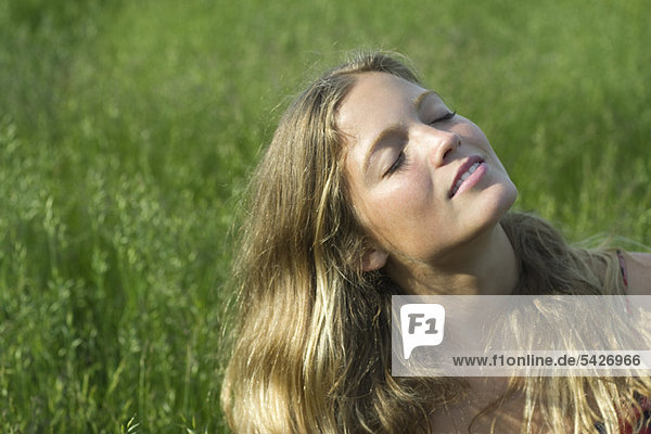 Junge Frau entspannt sich im Grasfeld