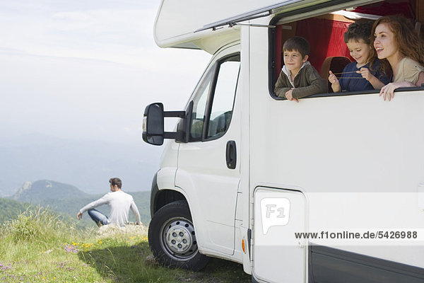Mother and young boys looking out motor home window