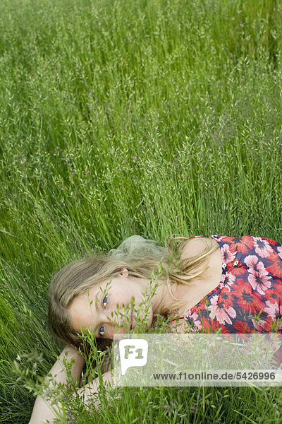 Junge Frau entspannt sich im hohen Gras