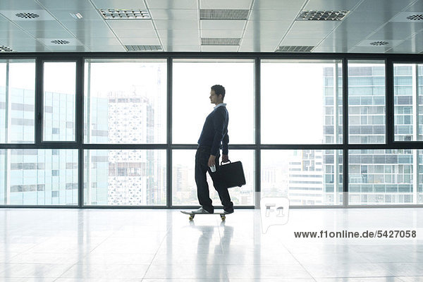Businessman standing on skateboard with briefcase