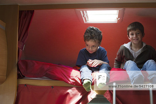 Junge Brüder im Wohnmobil auf dem Bett sitzend