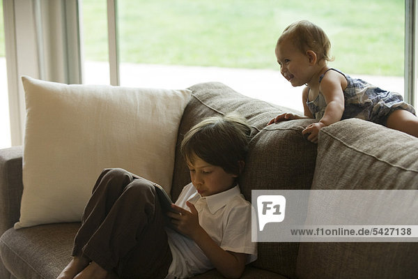 Junge entspannt auf dem Sofa  schaut auf digitales Tablett