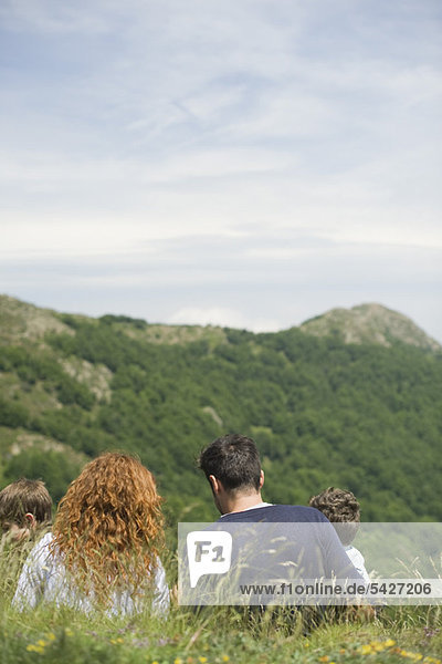 Eltern und Kinder auf der Wiese mit Blick auf die Berge  Rückansicht