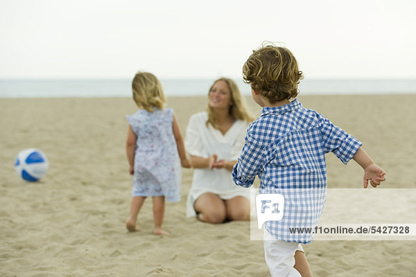 Junge spielt am Strand  Familie im Hintergrund