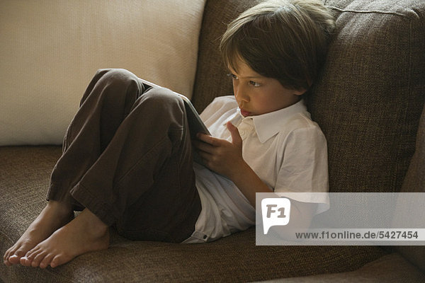 Junge entspannt auf Sofa mit digitalem Tablett