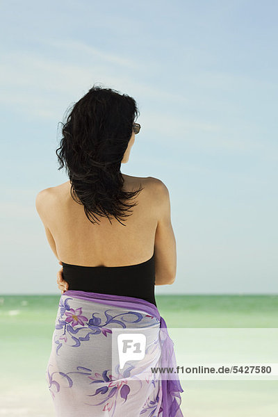 Frau am Strand mit Blick auf den Strand  Rückansicht