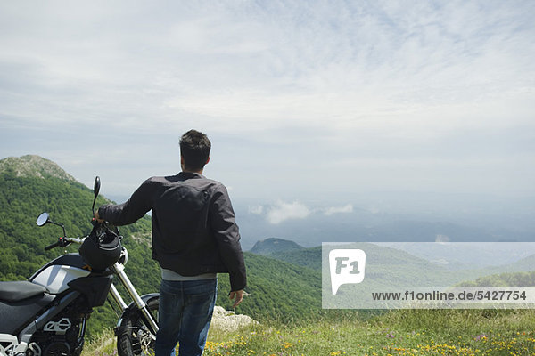 Man standing by motorcycle on mountain  rear view