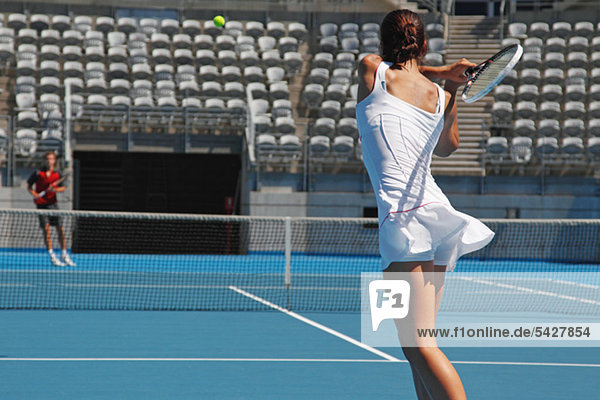 Junge männliche und weibliche Tennisspieler üben