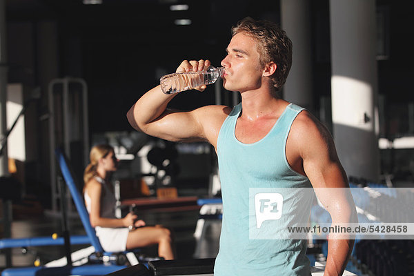 Junger Mann mit eine Pause während des physischen Trainings in ein Fitness-Studio