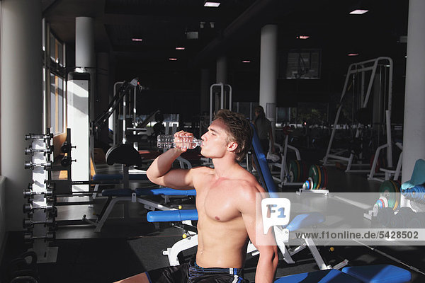 Junger Mann gekämpft Trinkwasser während des physischen Trainings in ein Fitness-Studio