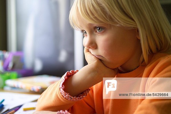 Mädchen sitzt traurig am Schreibtisch - ADHS Syndrom