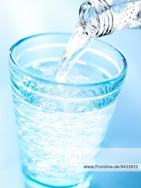 Wasser wird aus einer Flasche in ein Glas geschenkt - CO2 ( Wasser ) - H2O ( Kohlensäure )