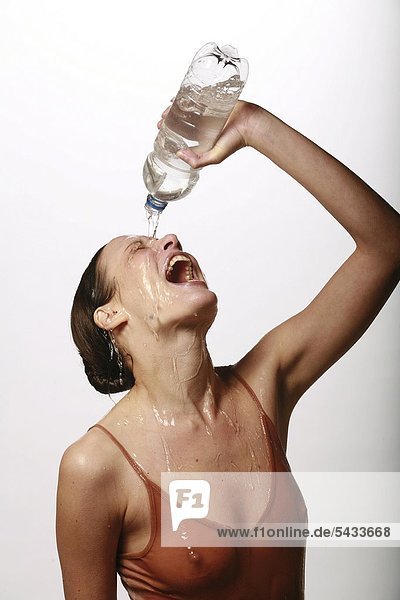 Eine lachende junge Frau gießt sich klares Wasser über Gesicht und Körper - woman - water - laughing mund