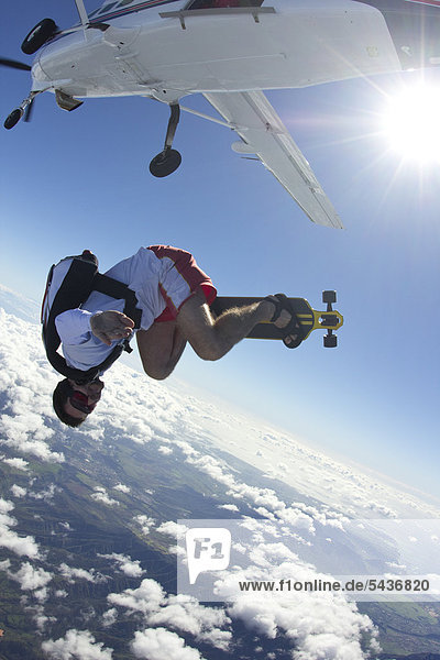 Fallschirmspringer mit Skateboard in der Luft
