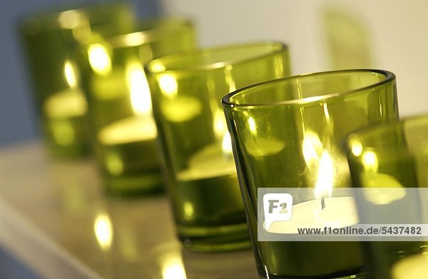 FünfTeelichter in grünen kleinen Gläsern in einer Reihe - Symbol für Tod -