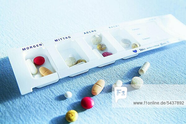 Tabletten und Pillen in Schachtel - Dose - Behälter - für einen Tag portioniert - einige Pillen liegen außerhalb -