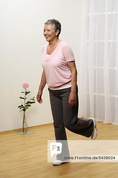 ältere Frau macht Gymnastik - Balance - Seniorin - Einbeinstand - Stand auf einem Bein