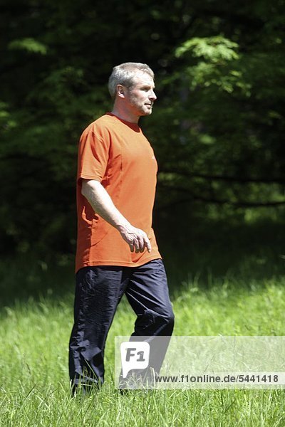 older man going für a walk on a meadow wearing sport clothes