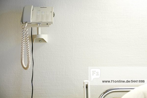 Krankenzimmer  ein Telefon hängt an der Wand neben einem Krankenbett.