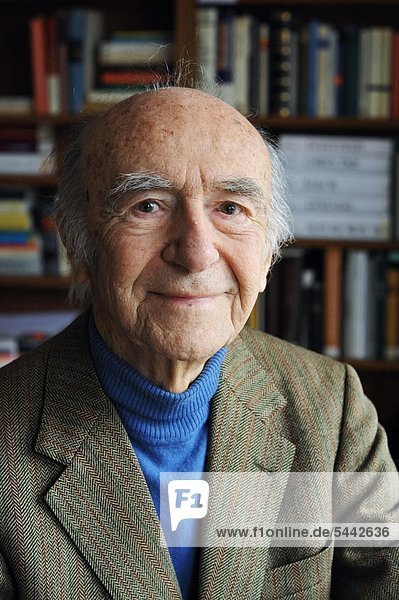 elderly man in front of a bookshelf