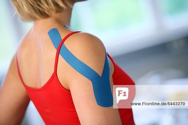 MEDI-TAPING : Triceps-Tape in Schulter- und Oberarmbereich einer jungen Frau