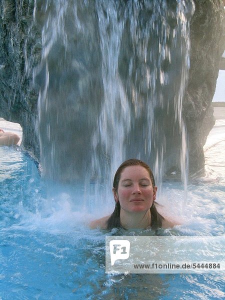 Frau entspannt unter einem künstlichen Wasserfall   Brause