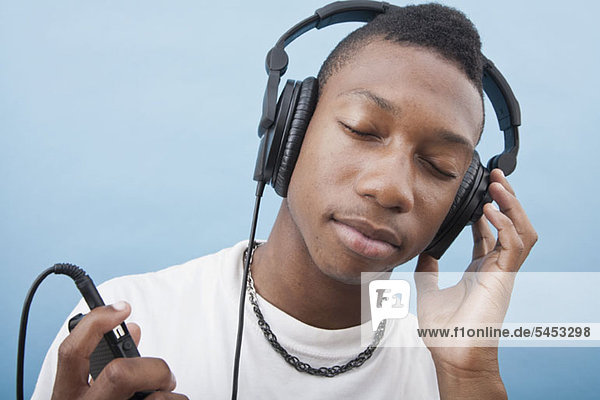 A young man listening to music with headphones  eyes closed