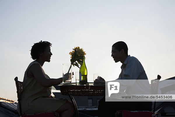 A couple dining on a rooftop terrace at sunset