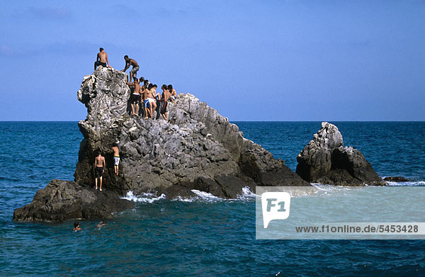 Eine Gruppe von Männern auf einem Felsen im Meer.