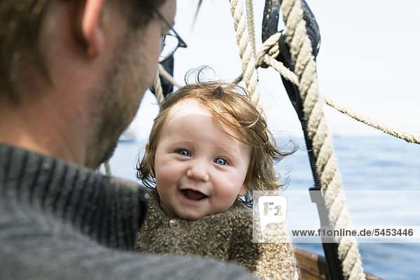 Ein aufgeregtes Baby mit ihrem Vater auf einem Boot