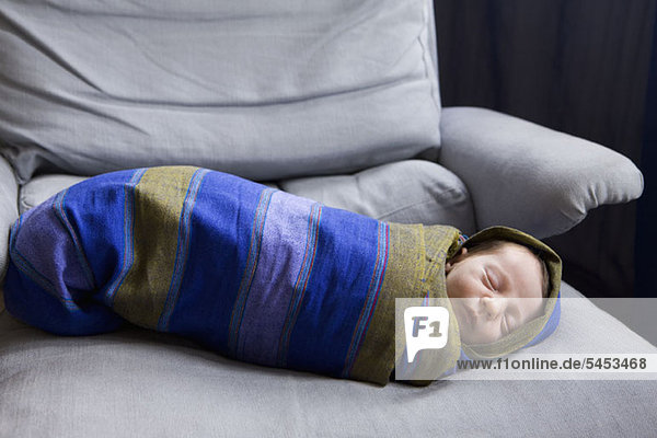 Ein neugeborenes Baby in einer gestreiften Decke gewickelt.