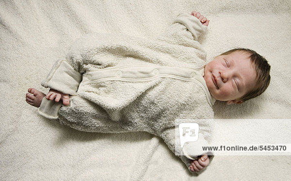 Ein schlafendes Neugeborenes mit ausgestreckten Armen.