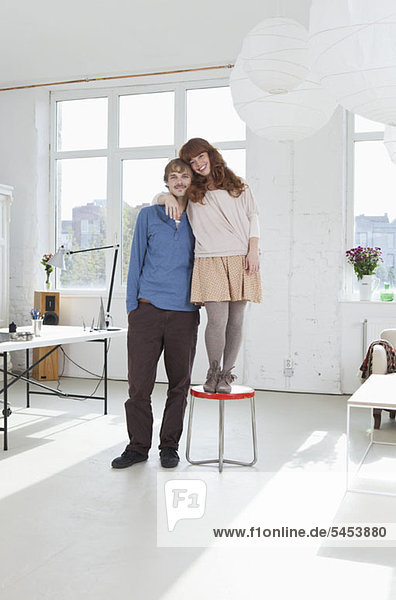 A young women standing on a stool next to her tall boyfriend