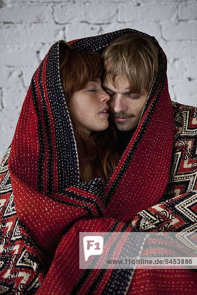A sensual young couple wrapped in a blanket