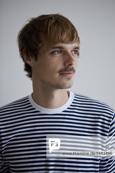 A young man in a striped t-shirt looking away