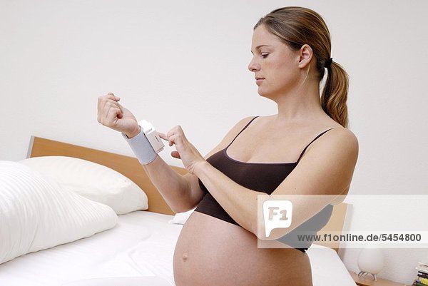 Schwangere Frau misst ihren Blutdruck