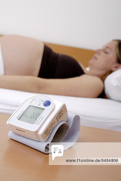 Liegende schwangere Frau mit Blutdruckmessgerät